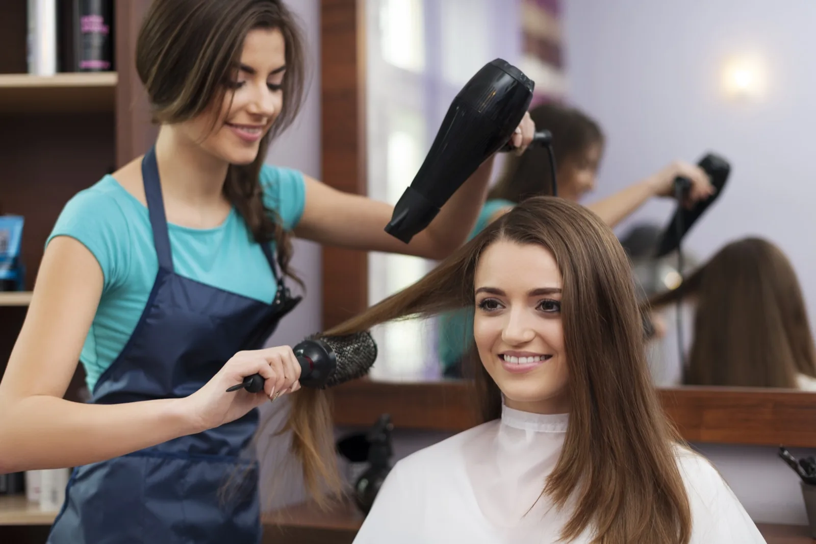 Cabeleireira usando escova e secador na cliente